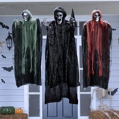 Three hanging grim reapers in green, black and orange hanging on a front porch with pumpkins